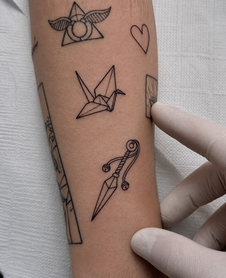 Fine line flash tattoos including an origami crane and small symbols by a Manchester Fine Line Tattoo Academy student